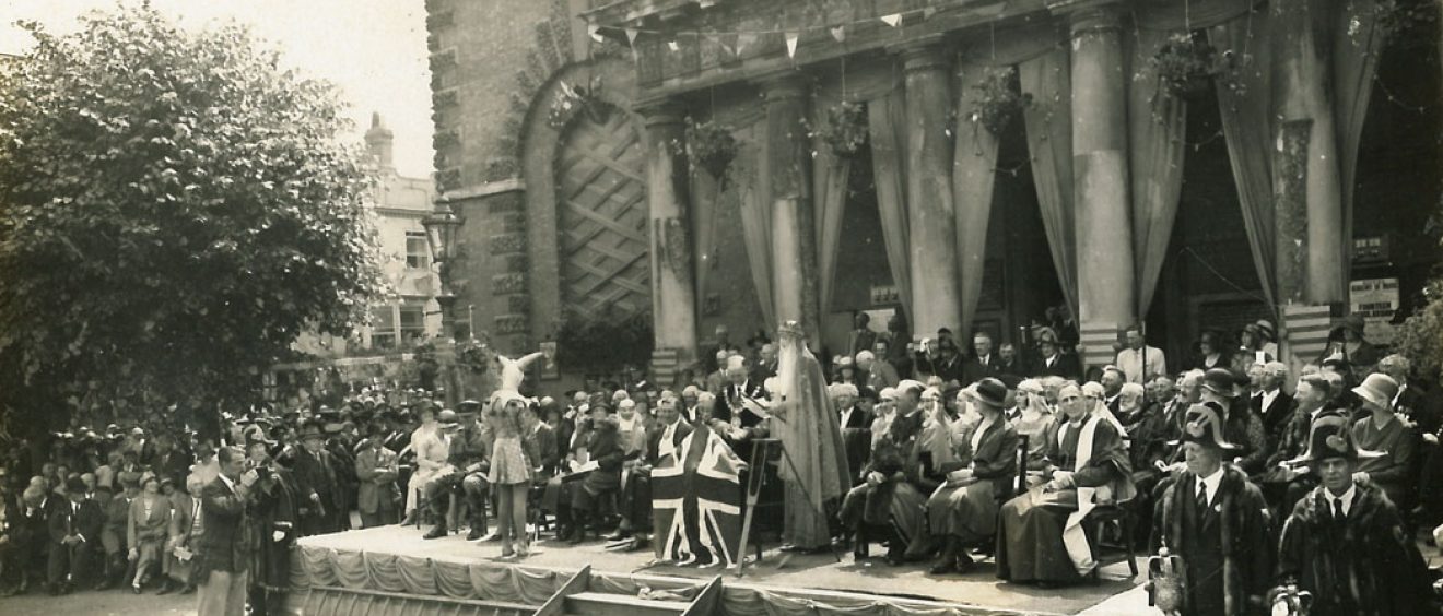 Audience and dignitaries seated on platform outside town hall