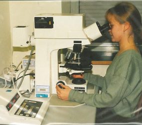 woman viewing samples through powerful multi-lens microscope