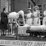 Model stork with mother in bed and maternity staff on back of carnival float