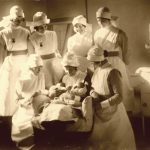 Maternity nurses gathering round the babies