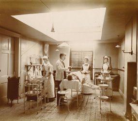 Patient on operating table with lighting, equipment nurses and doctor attending