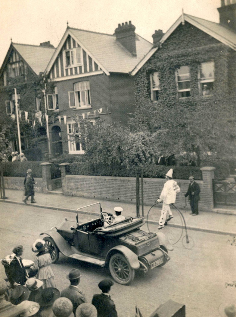 Salisbury Peace Parade, 1919 – car drives alongside a clown on a penny farthing