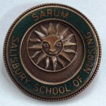 Metal badge with sun inscription inside green circle
