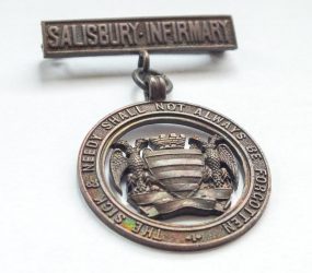 bronze metal badge with Salisbury city crest and Infirmary motto
