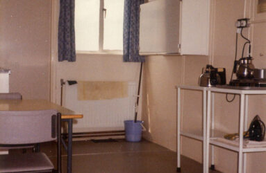 a colour photograph of small kitchen, wall unit and trolley with kettle