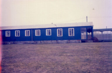 a colour photograph of blue hut with white windows