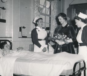 Princess Alexandra next to boy in bed with two nurses