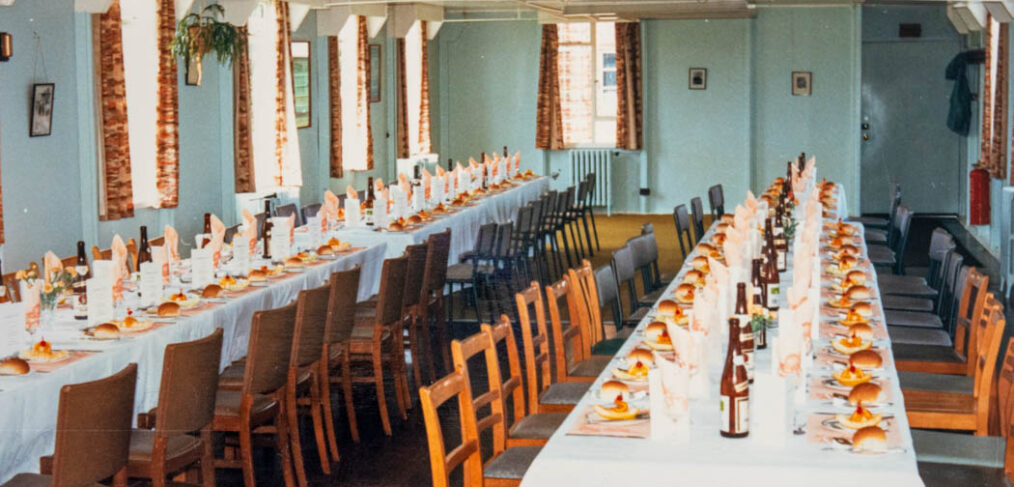 A colour photograph of 2 long tables laid up for lunch with bottles
