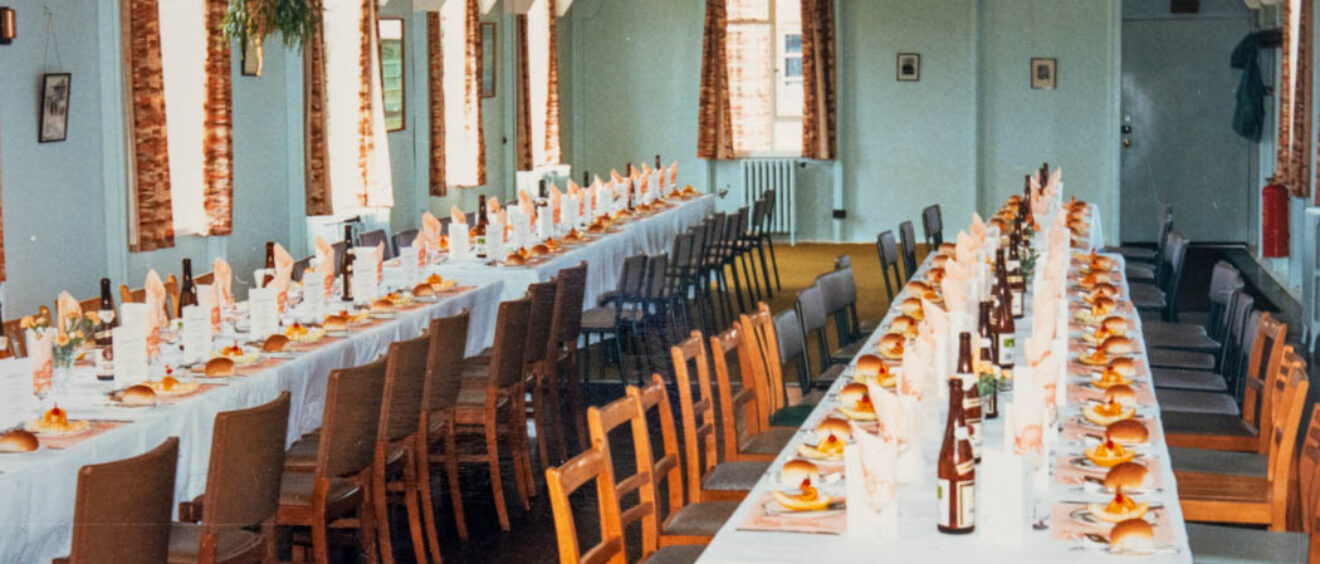 A colour photograph of 2 long tables laid up for lunch with bottles