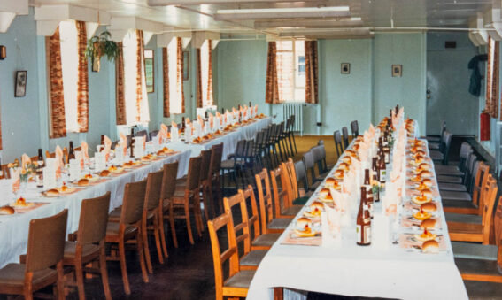 A colour photograph of 2 long tables laid up for lunch with bottles