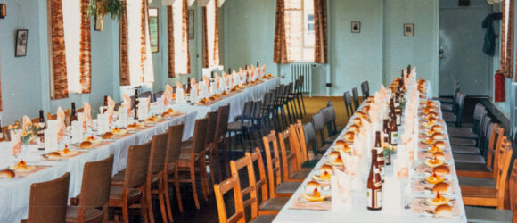 A colour photograph of 2 long tables laid up for lunch with bottles