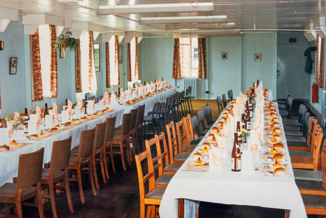 A colour photograph of 2 long tables laid up for lunch with bottles