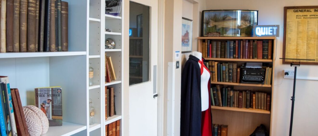 Photograph of history room with book shelves and nurse uniform mannequin