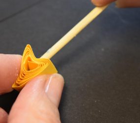 using a pencil to squash one side of a paper coil inwards