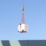 MRI scanner dangling on end of crane hook above roof