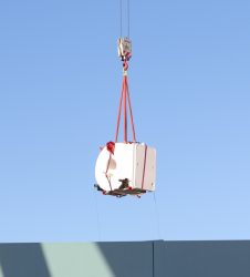 MRI scanner dangling on end of crane hook above roof