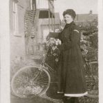 Cook in dark uniform posing with her bike in hospital grounds