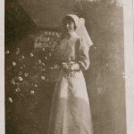 Nurse poses in garden, flowers and church in background