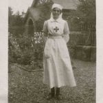 Nurse stands in the garden, church in the background