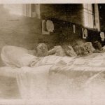 Three soldiers in bed pose for the camera