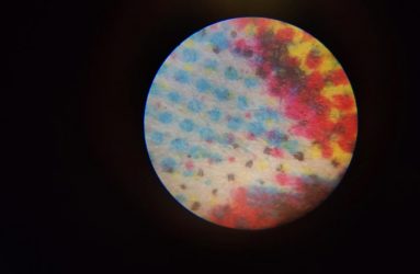 CMYK coloured dots that make up newspaper print viewed under a microscope