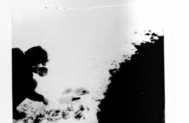 a black and white photo of person placing bottle in snow