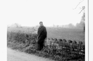 a black and white photo of women leaning on stone wall
