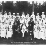 Nurses and other hospital staff seated and standing in rows for photograph