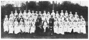 Nurses and other hospital staff seated and standing in rows for photograph