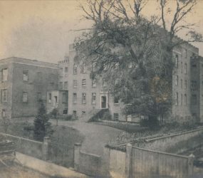 Infirmary viewed from the front, large tree in foreground