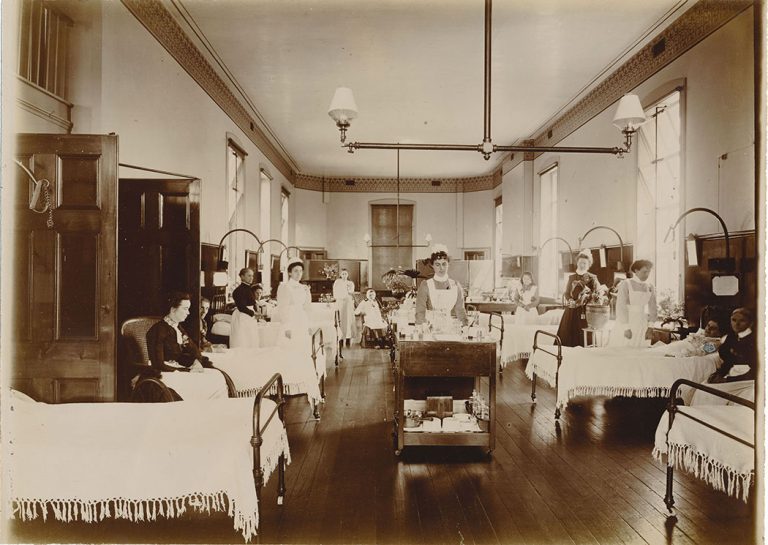 Patients in beds or wheelchairs with nurses attending