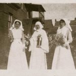 Nurses and nun in uniforms posing in garden outside hospital