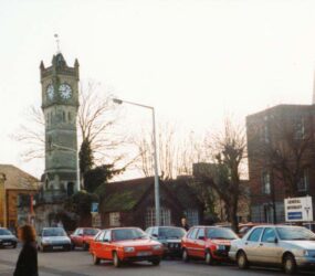 Colour photograph of street with cars and clock tower
