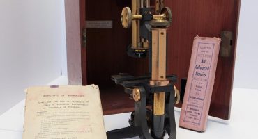 1920s metal optical microscope with wooden box, University of Edinburgh notes and pack of six coloured pencils in pink box