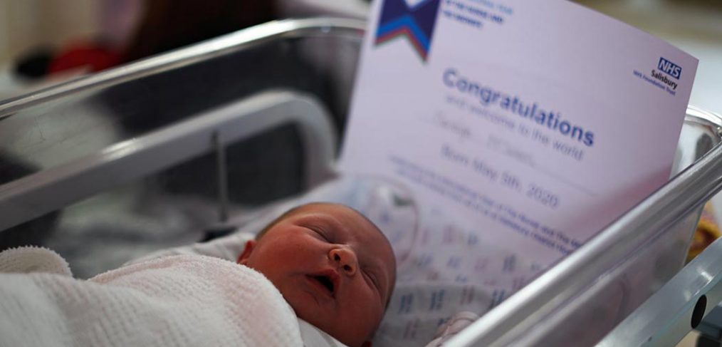 newborn baby in cot with certificate