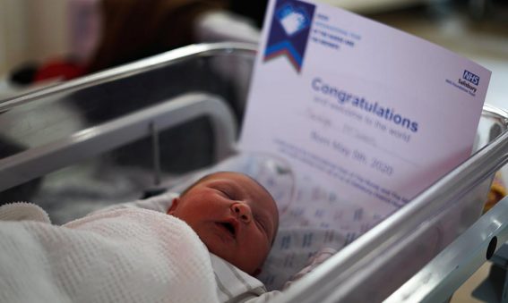 newborn baby in cot with certificate