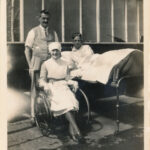 Black and white photograph of hospital bed, nurse and wheelchair