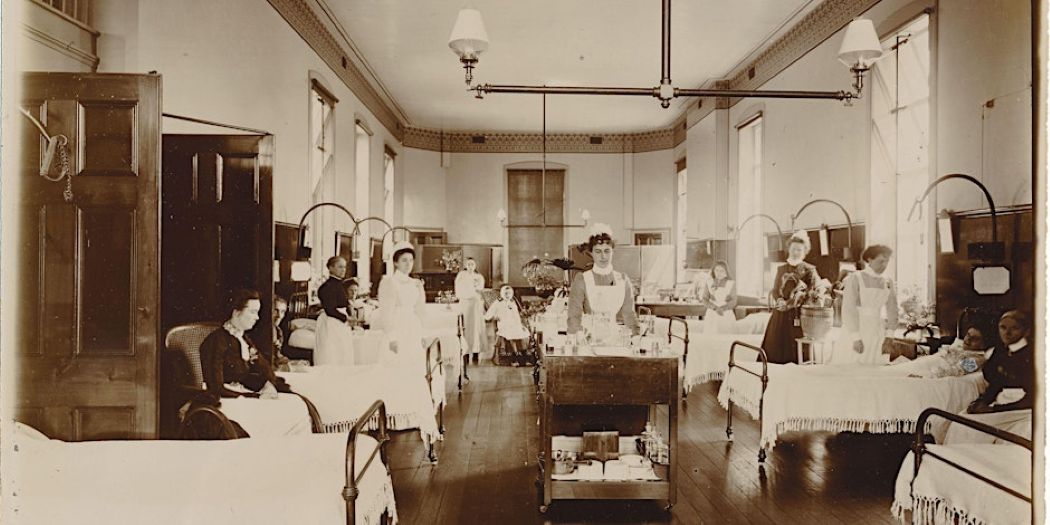 Sepia photograph of hospital ward with nurses and beds
