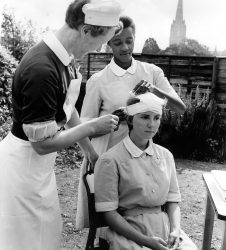 Two nurses bandaging another's head