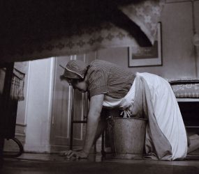 Cleaner on hands and knees with bucket scrubbing floor