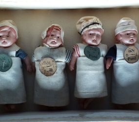 Small dolls in box dressed in scrap materials from nursing uniforms