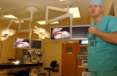 Surgeon with digital image screens mounted on ceiling in operating theatre