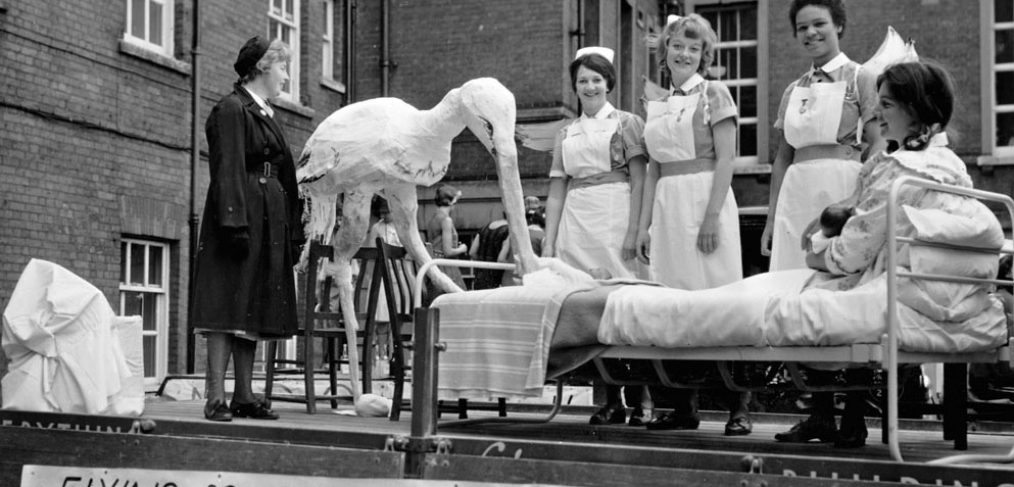 maternity themed float with mother and baby in bed, stork and staff
