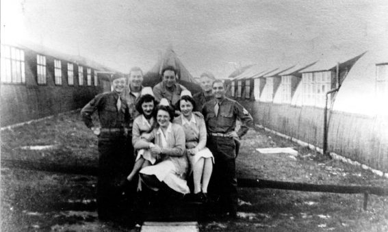 Soldiers and nurses posing for photo between Nissen huts