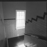 staircase with tiled walls, window and handrail down to tunnels