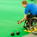 man in wheelchair getting ready to bowl a ball