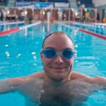 man wearing goggles looking straight to camera at end of pool